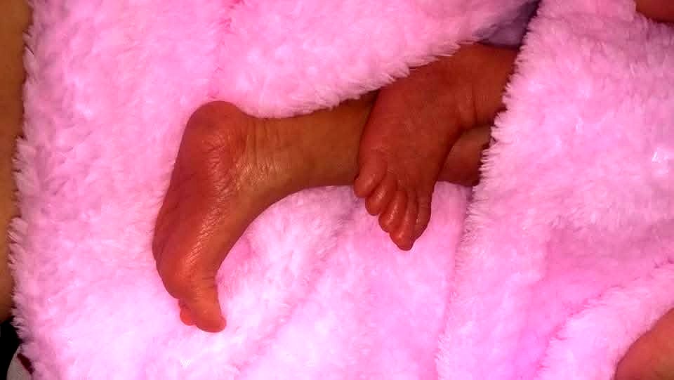 Tiny newborn feet wrapped in a soft pink blanket